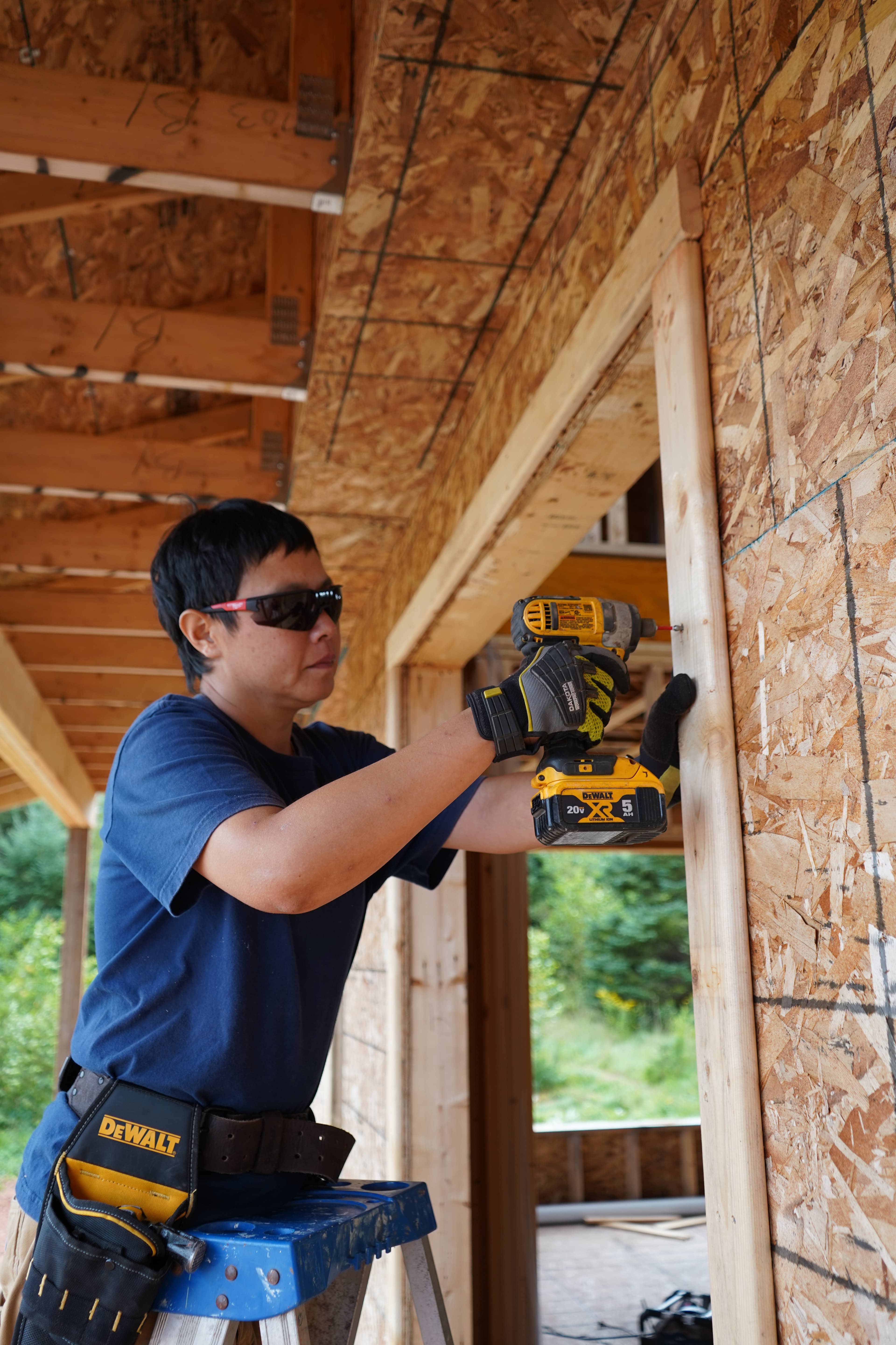 A tradesperson fastening a wood door frame with an impact driver