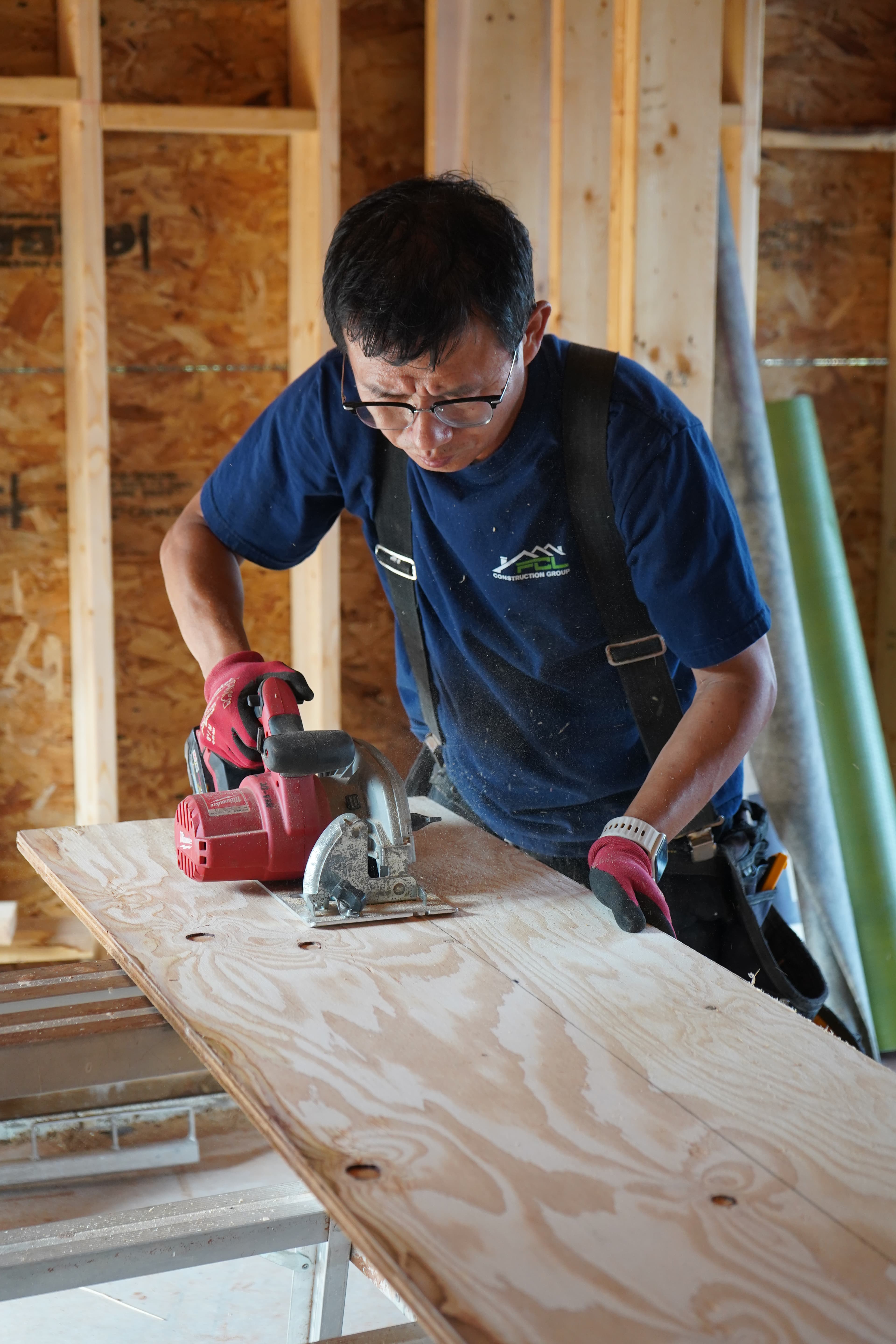 A tradesperson cutting a plywood sheet with a circular saw